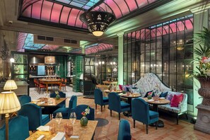 A restaurant with a high ceiling, large windows, and a mix of seating including tables and a sofa. - Helvetia & Bristol Firenze – Starhotels Collezione (Florence)