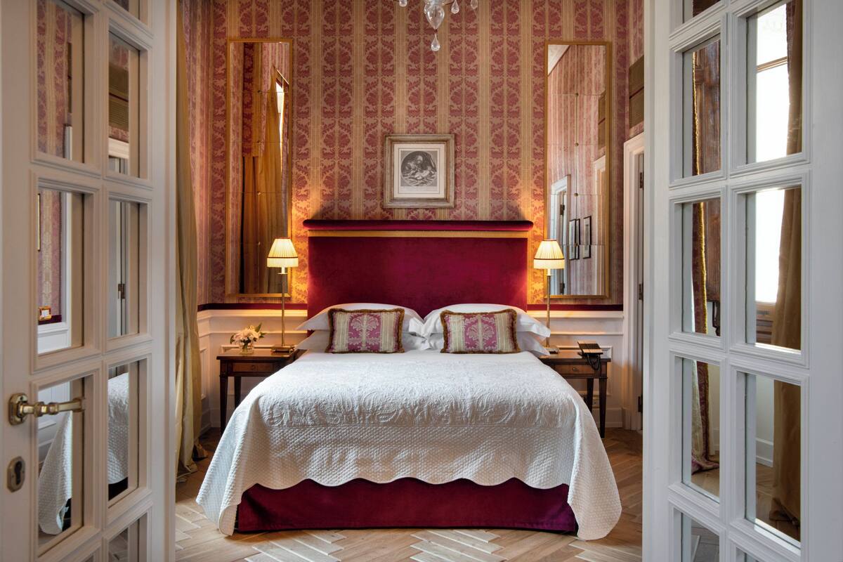 A hotel room with a large bed, a red headboard, and a framed picture on the wall.