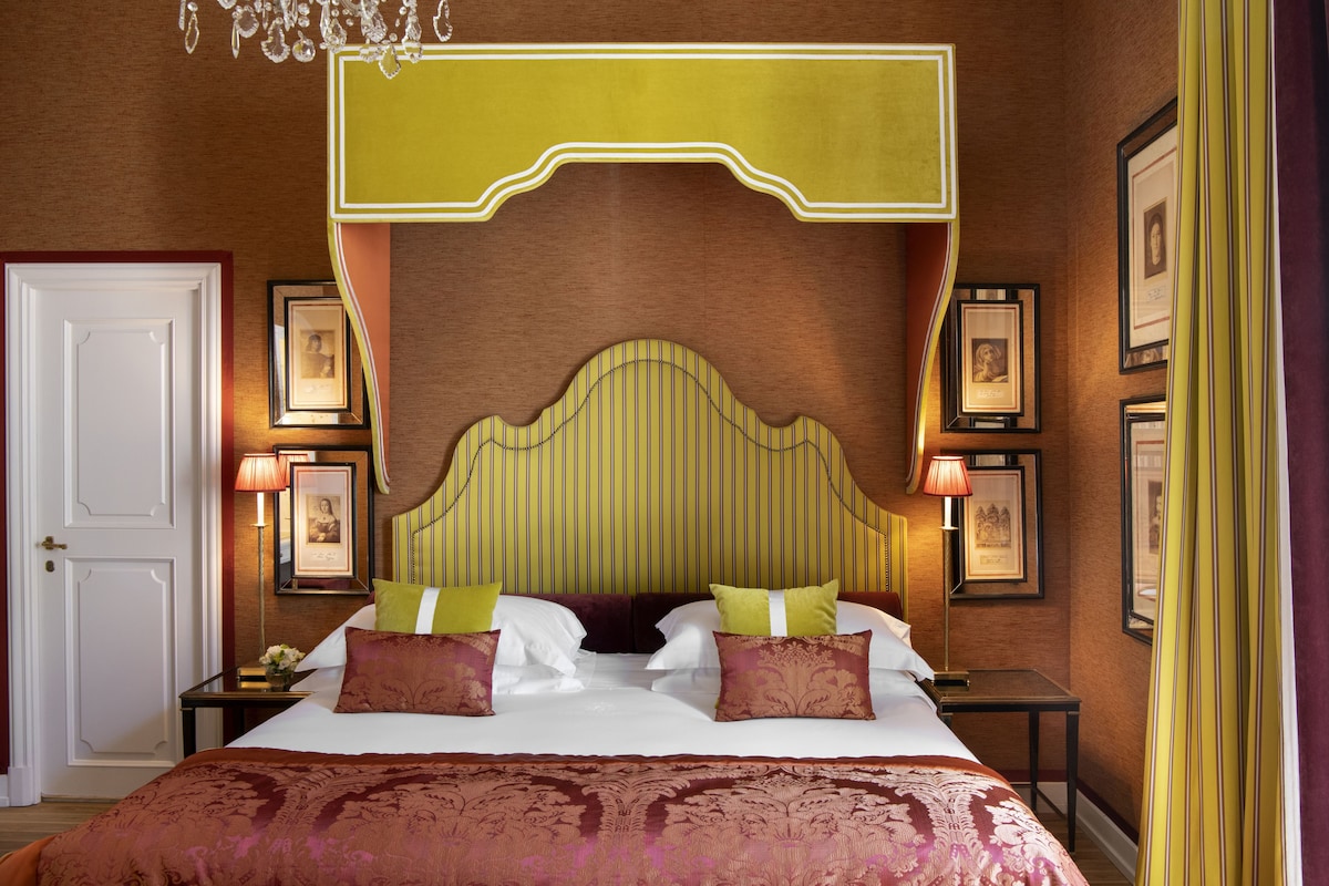 Una habitación de hotel con una cama grande, cuadros en las paredes y un candelabro.