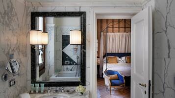 A bathroom with a marble sink, two wall-mounted lamps, and a large mirror.