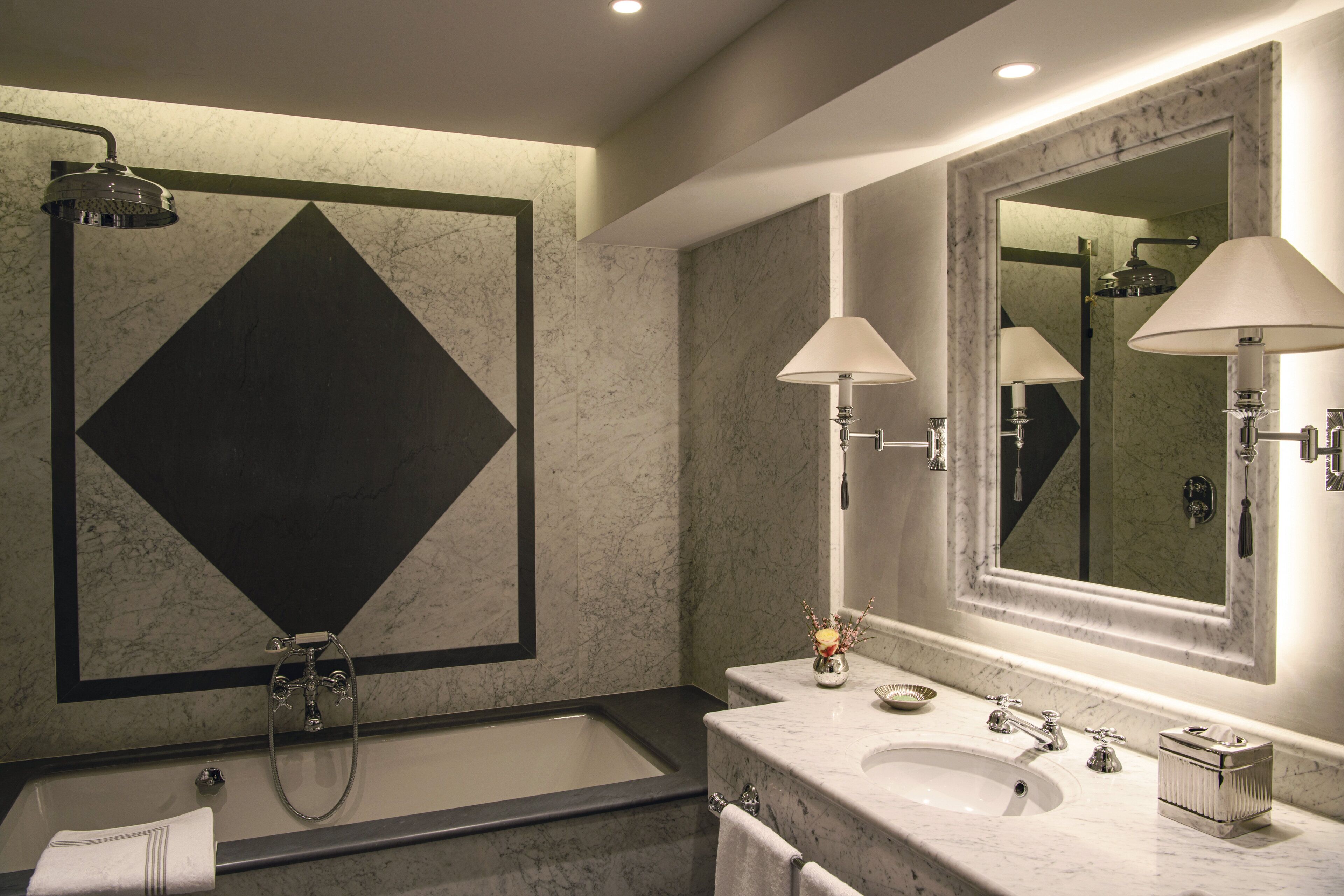 Un bagno moderno con uno specchio grande, una vasca e un lavandino.