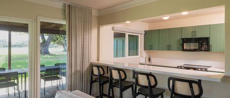 Una cocina moderna con barra, zona de comedor con asientos exteriores y puerta corredera de vidrio que da a un patio.