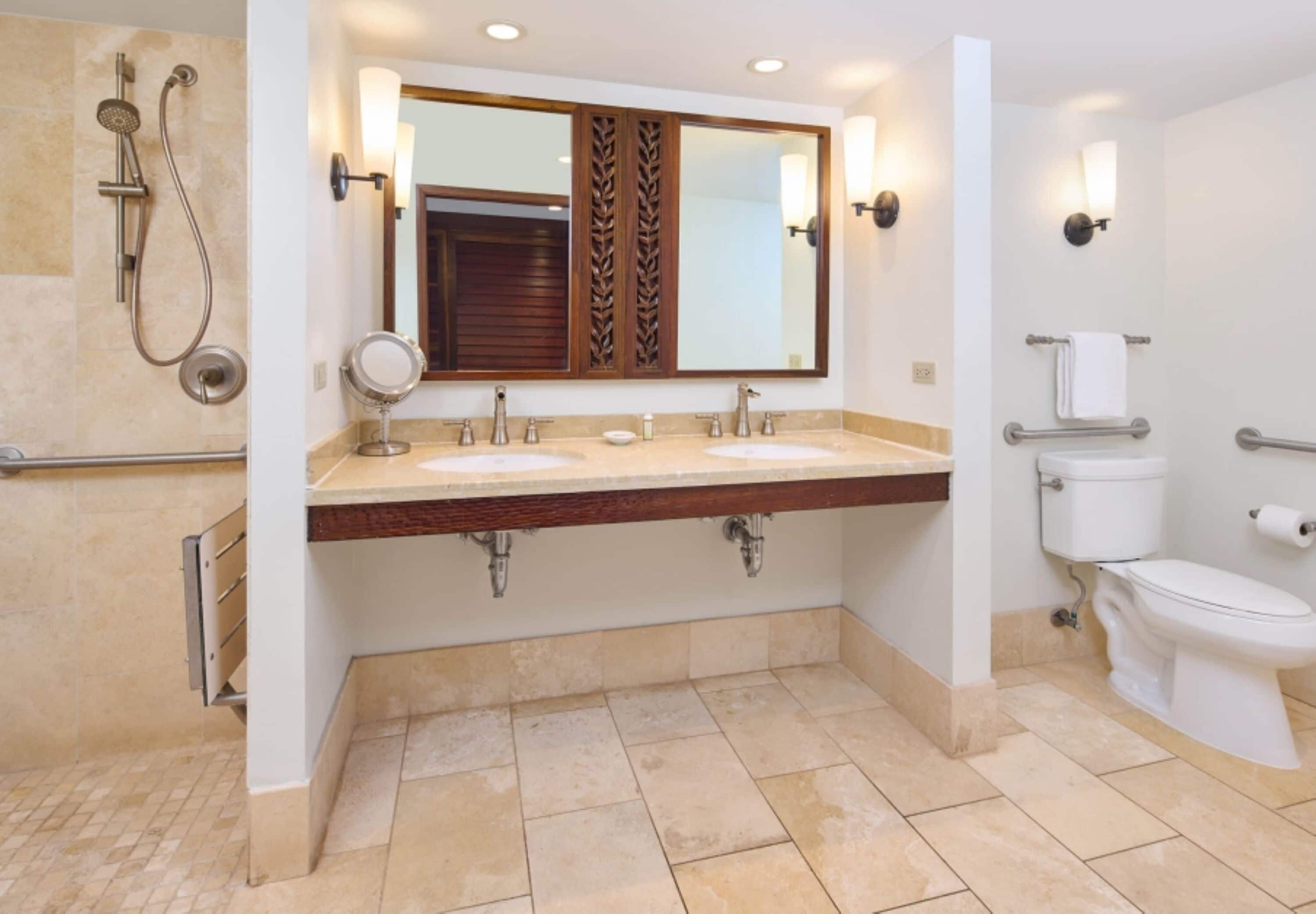 A bathroom with two sinks, a shower, a toilet, and a large mirror with wall sconces.