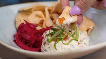 A bowl of dip with tortilla chips and a side of pickled red onions.