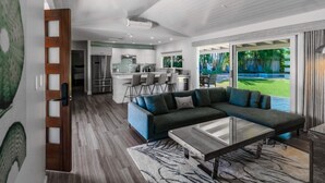 A modern living room with a sectional sofa, a glass coffee table, and a view of the backyard.