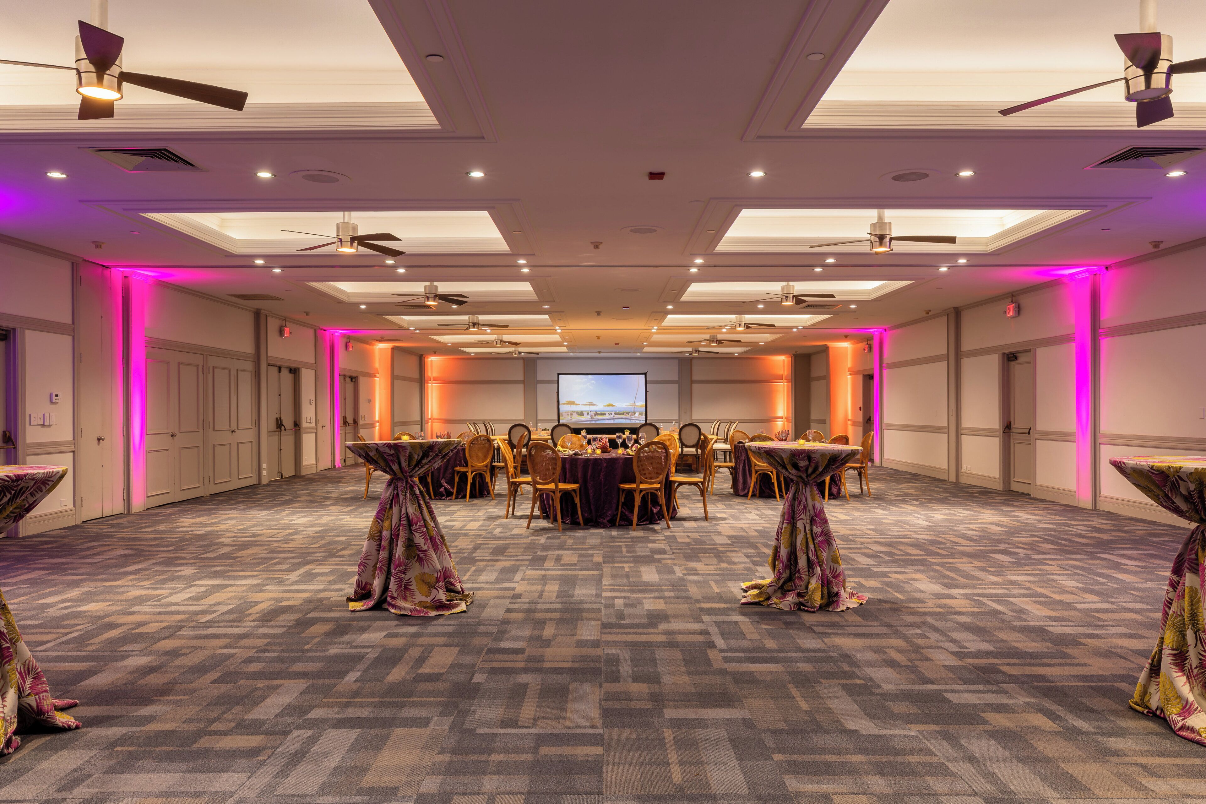 A conference room with a large table, chairs, and a screen at the front.