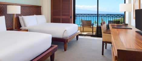 Une chambre d’hôtel avec deux lits, un bureau, une chaise, une télévision et un balcon avec vue sur l’océan.