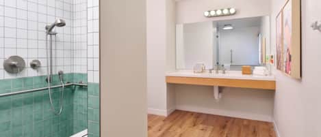 Un baño con ducha, lavamanos y espejo con iluminación.