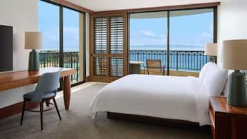 Habitación de hotel con una cama grande, un escritorio, una silla y vista al océano.