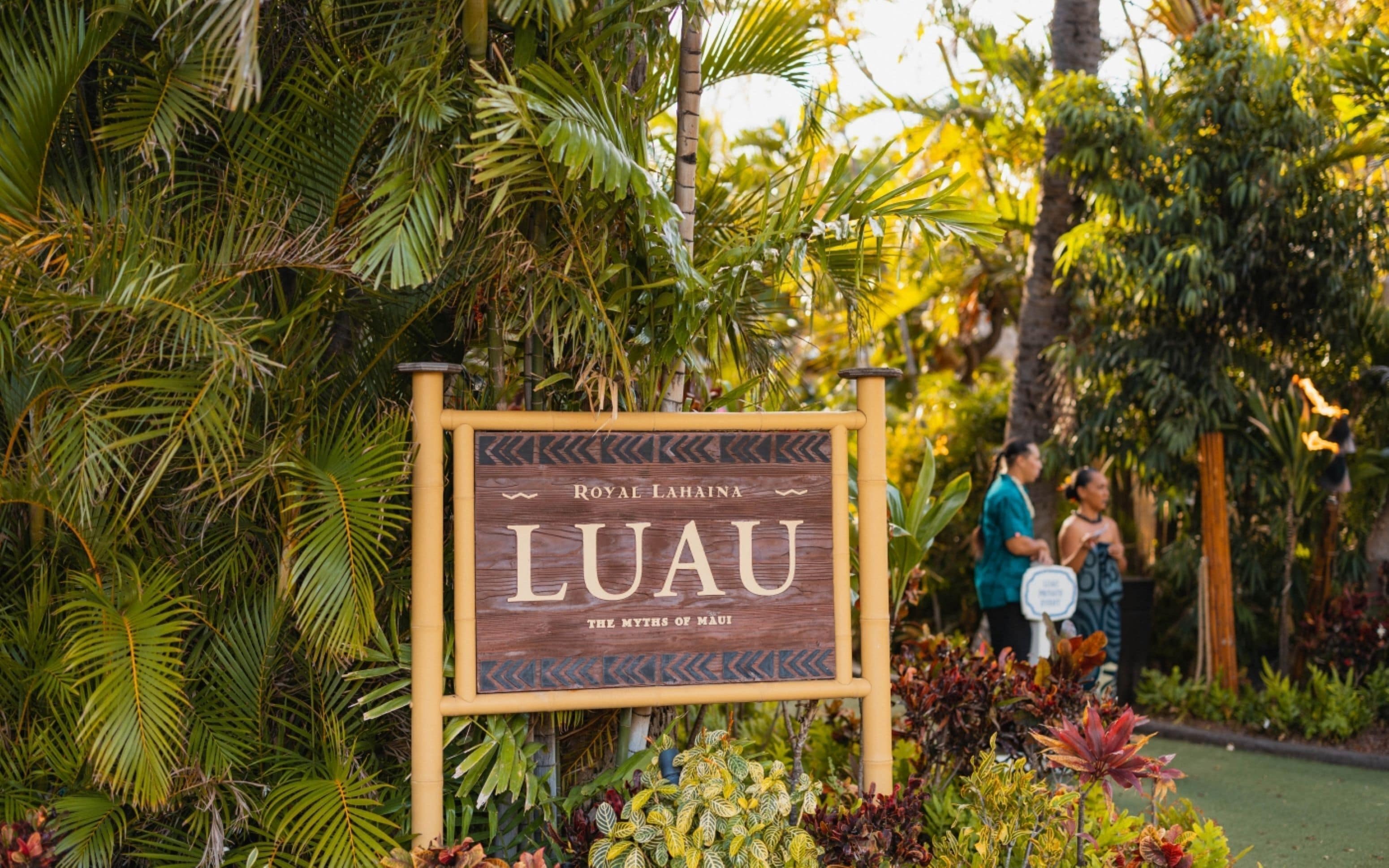 A sign for 'Royal Lahaina Luau' with a tropical garden background.