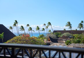 Un resort con vista al océano, palmeras y una terraza de madera.
