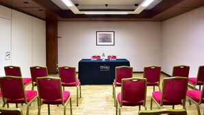 Una sala de conferencias con una mesa que indica 'TIVOLI HOTELS & RESORTS', sillas rojas y un cuadro en la pared.