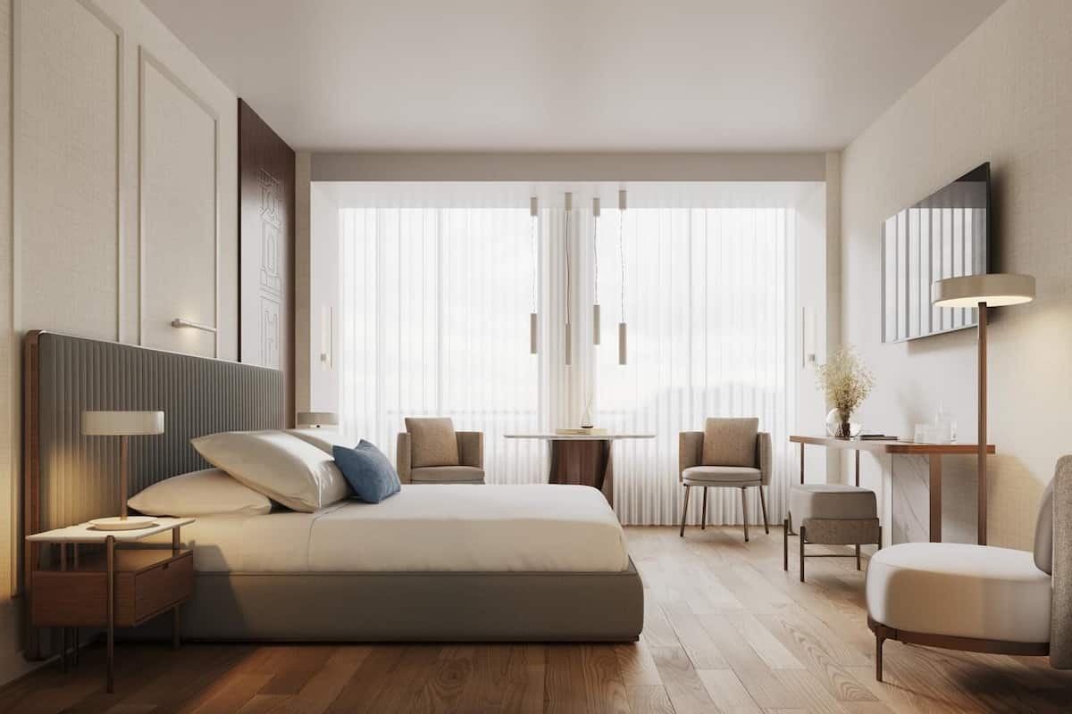 Una habitación de hotel moderna con una cama grande, mesitas de noche, un escritorio y una silla.