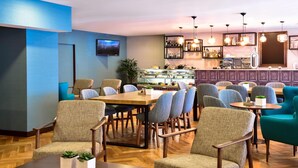 Un restaurante con zona de bar, diversas opciones de asientos y una pantalla de televisión.