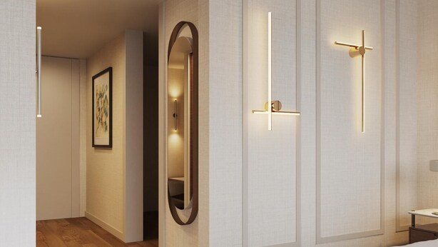 Una habitación de hotel moderna con piso de madera, una cama grande, una mesita de noche, un espejo e iluminación empotrada.