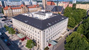 A multi-story hotel with a prominent central tower, large windows, and a red awning. - Hotel Chemnitzer Hof (Chemnitz)
