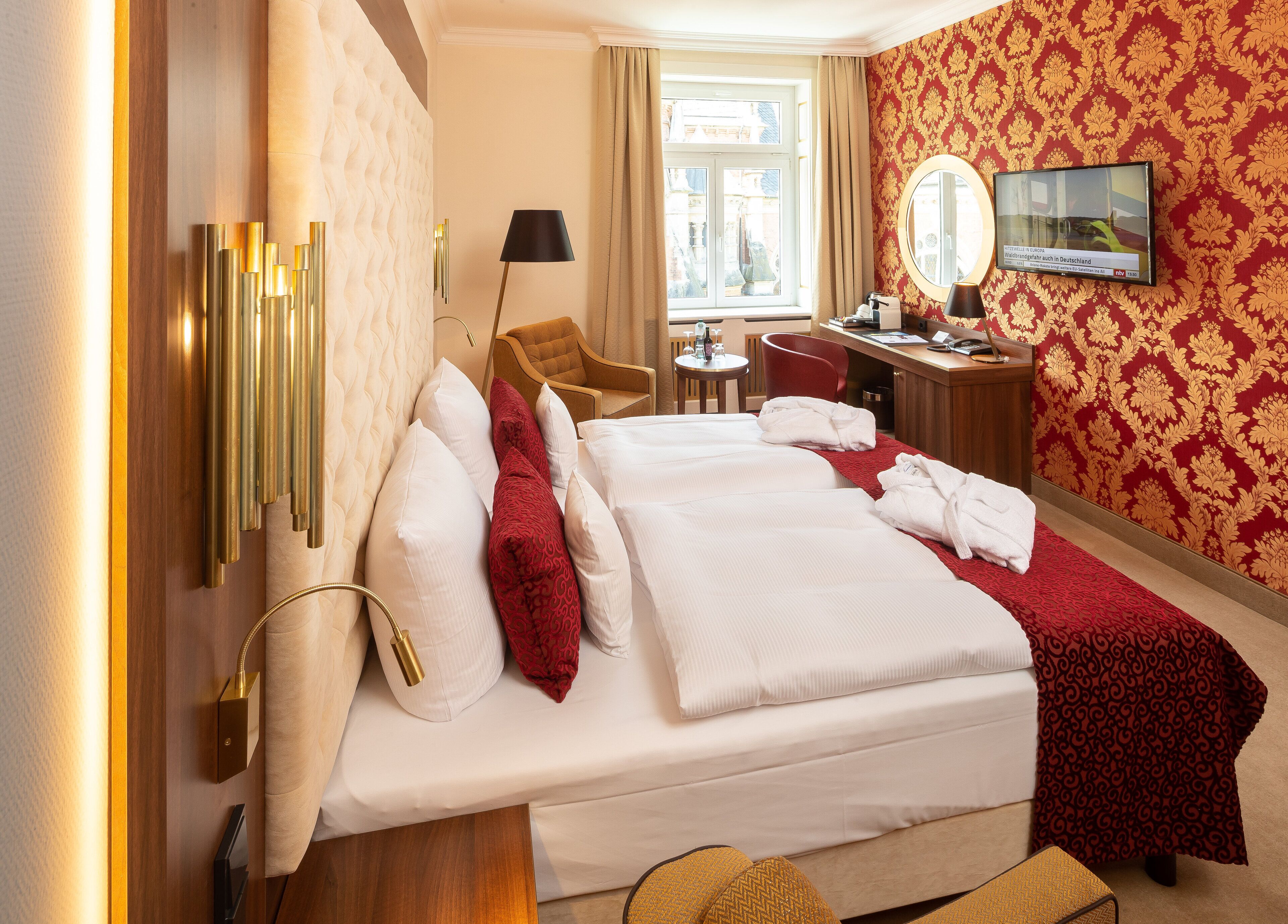 A hotel room with a bed, a desk, a chair, and a TV.