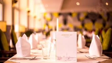 A table set with white napkins, cutlery, and a glass. A menu titled "CHEMNITZER HOF" is placed on the table.
