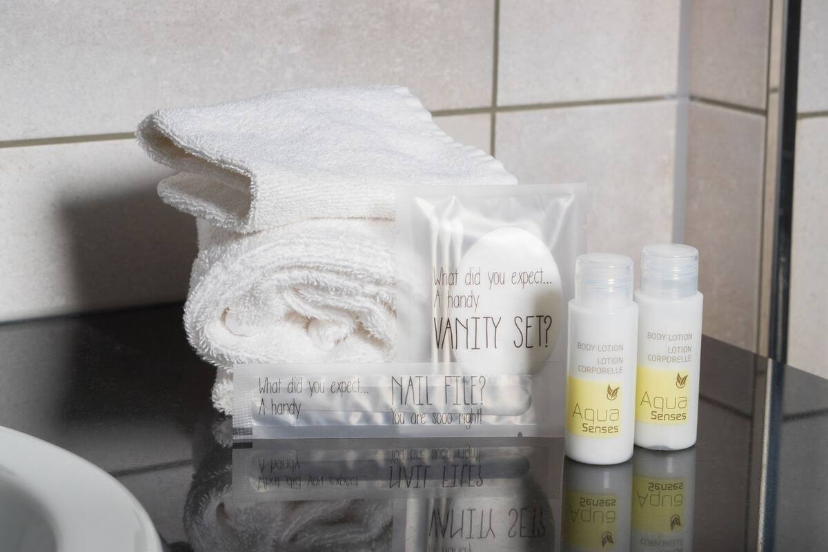 A bathroom vanity set with a towel, a mirror, and two body lotion bottles.