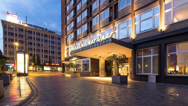 A hotel entrance with a modern facade, large windows, and a well-lit entrance area.
