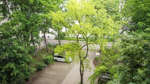 A parking area with a white car, surrounded by trees and a paved walkway.