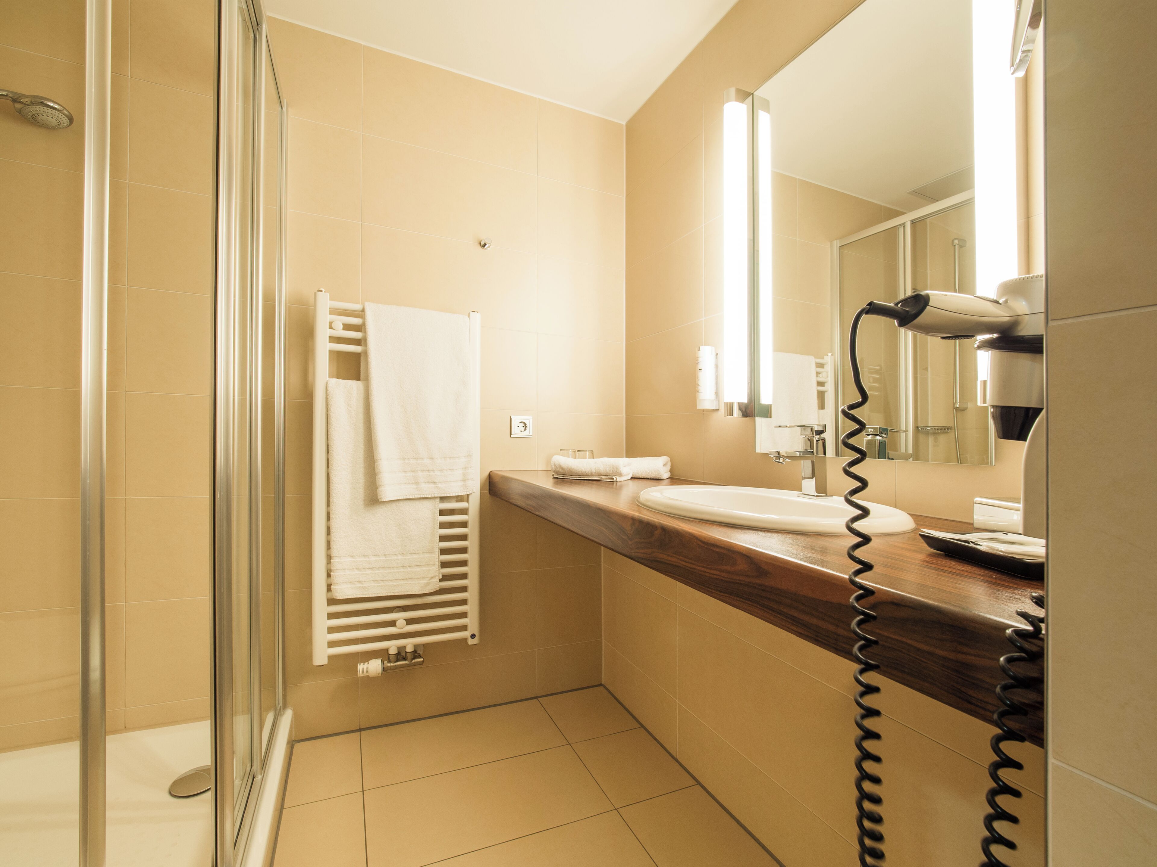 Ein Badezimmer mit Dusche, Waschbecken, Spiegel und Haartrockner.