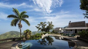 Un resort con piscina cristalina, palmeras y vistas a las montañas.