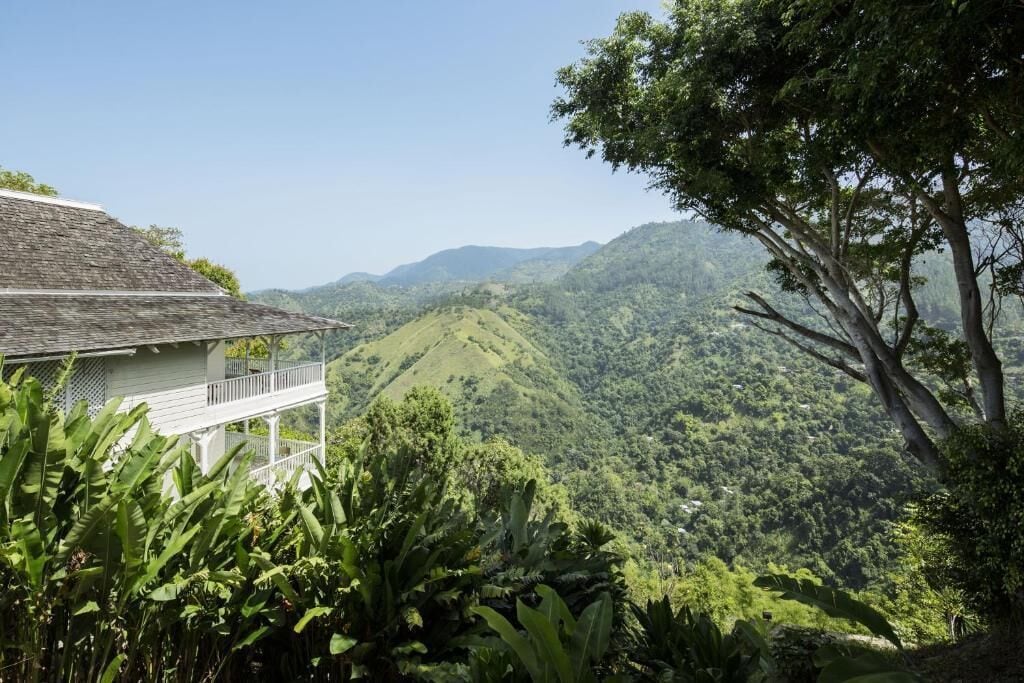 A house with a balcony overlooking a lush green valley and distant hills.