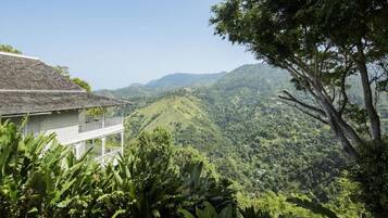 A house with a balcony overlooking a lush green valley and distant hills.
