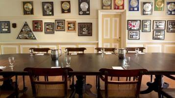 A dining area with a long table, multiple chairs, and framed awards on the wall.
