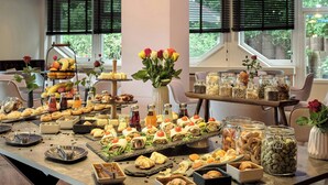 Una mesa de buffet con diversos alimentos y un jarrón de flores.