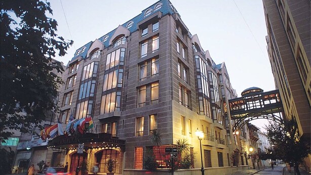 A multi-story hotel with a modern architectural design, featuring large windows and a prominent entrance with flags. - Hotel Fundador (Santiago)