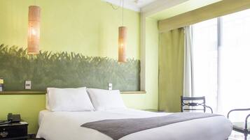 Una camera d'albergo con un letto grande, un comodino, una sedia e una finestra con tende.