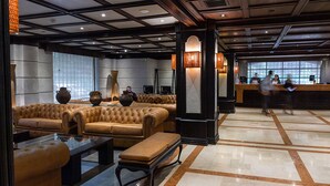 A lobby with a seating area, a reception desk, and a large window. - Hotel Fundador (Santiago)