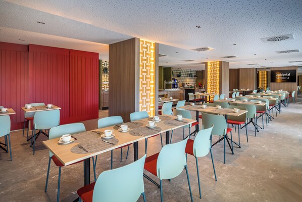 A spacious dining area with multiple tables and chairs, a red curtain backdrop, and a modern ceiling design. - Occidental Pamplona (Pamplona)