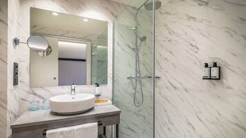 Une salle de bain moderne avec un mur en marbre, un lavabo rond, une douche en verre et un miroir au-dessus du lavabo.