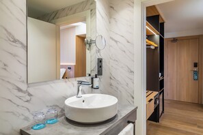 Un baño con lavamanos de mármol, un espejo y una puerta de madera.
