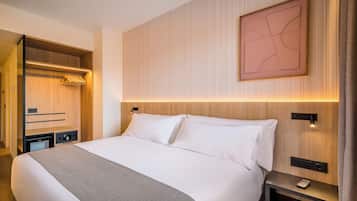 Habitación de hotel con una cama grande, un armario de madera, una mesita de noche con teléfono y una obra de arte colgada en la pared.