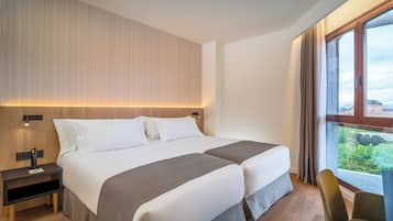 A hotel room with two beds, a nightstand, a chair, and a large window with a view.
