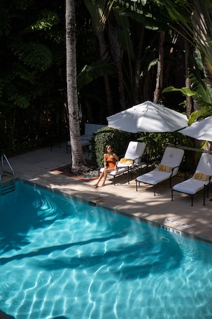Una piscina al aire libre, sombrillas, sillones reclinables de piscina