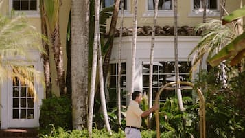 Experience a serene getaway amidst lush gardens and a classic, two-story building with a balcony offering a view of the surroundings.
