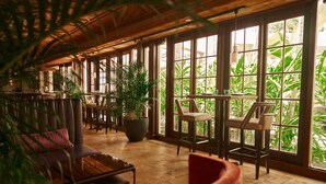 Un espacio interior amplio con ventanas grandes, techo de madera y asientos cómodos.
