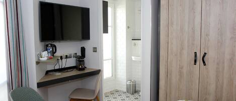 A compact room with a bed, a desk with a chair, a television, and a wardrobe.