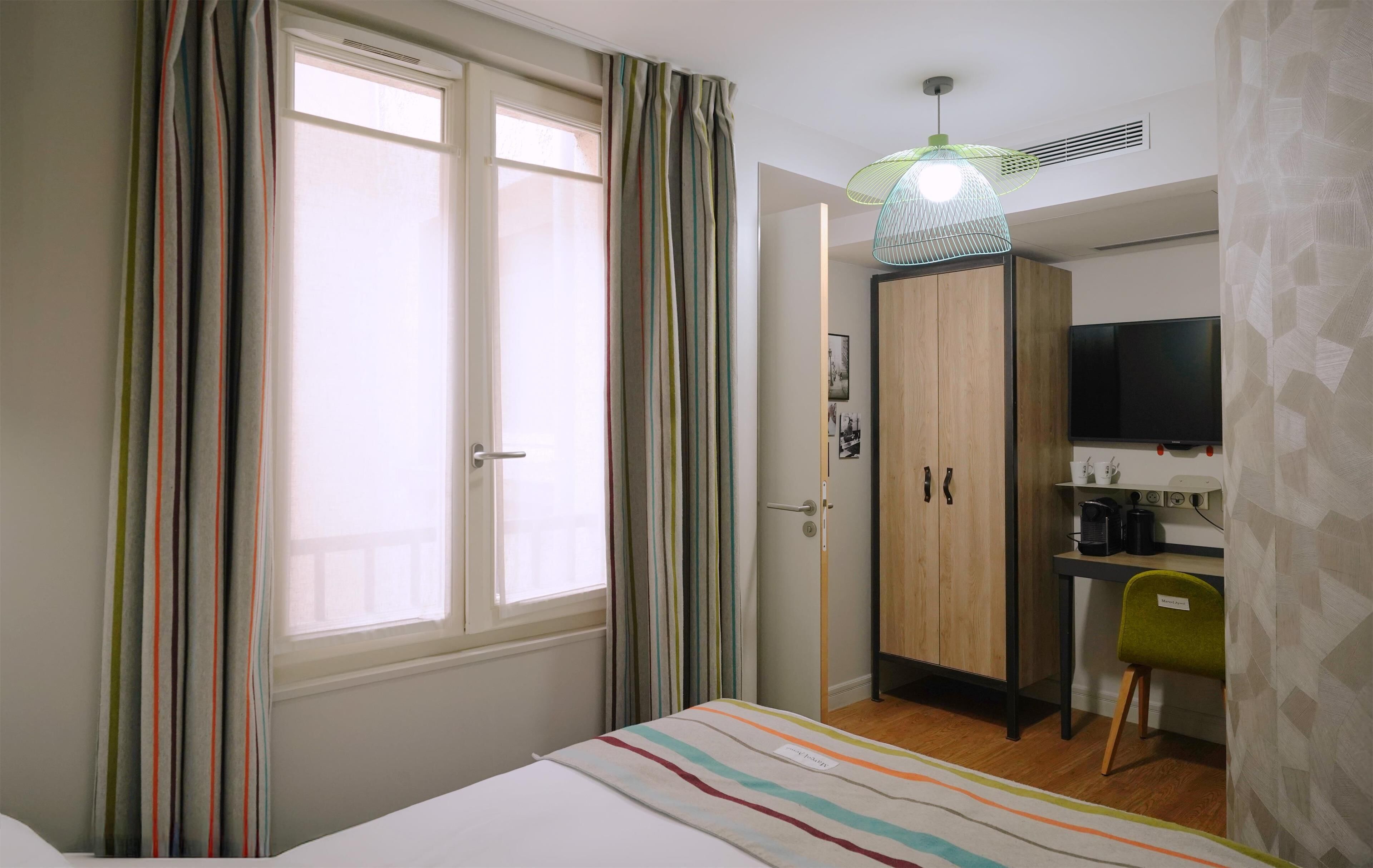 Ein Schlafzimmer mit Bett, Schreibtisch, Stuhl, Kleiderschrank und Fernseher.