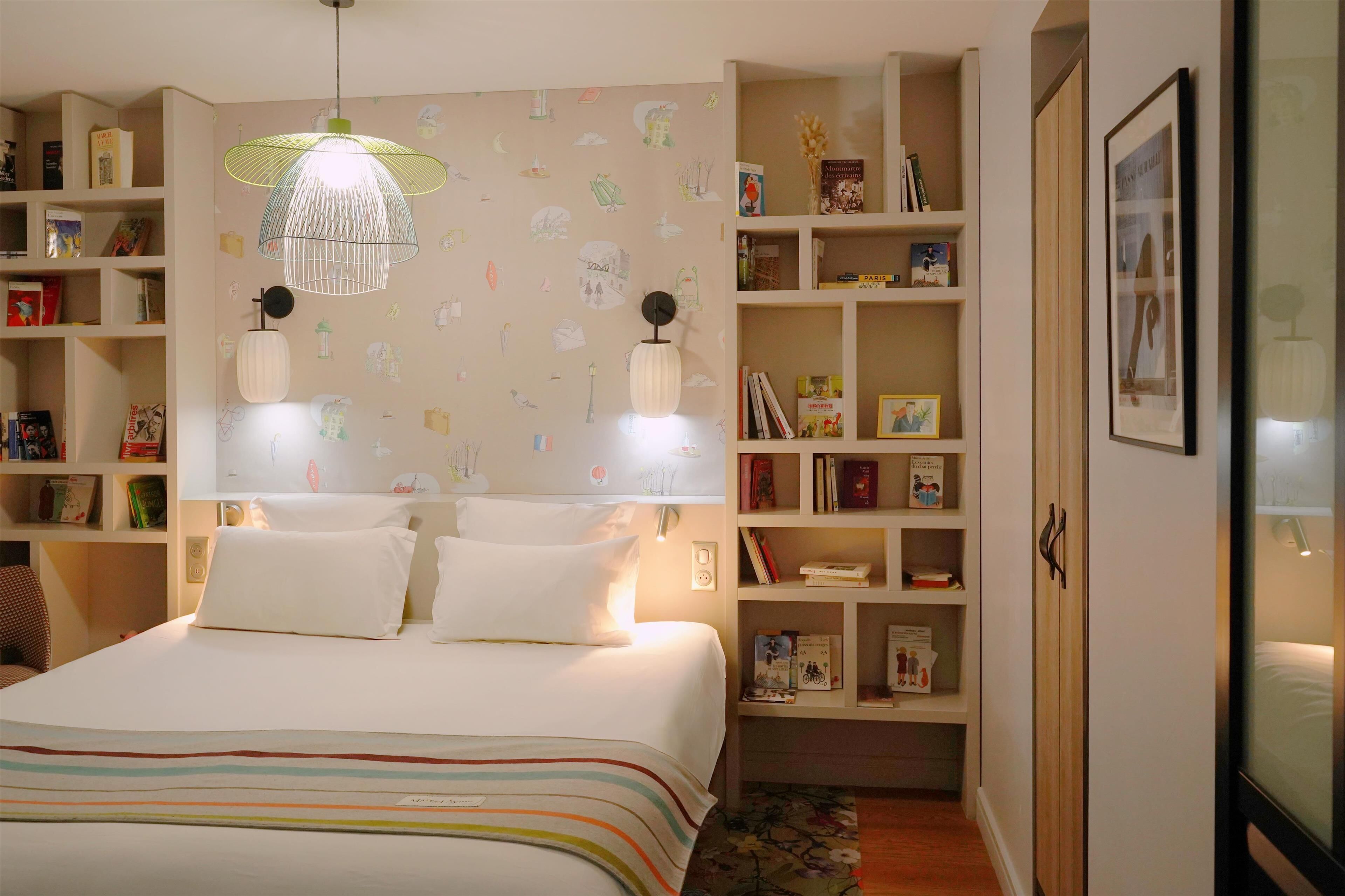 A neatly organized bedroom with a large bed, two bedside tables, a bookshelf, and a hanging light fixture.