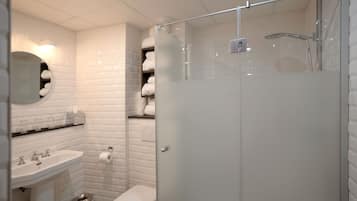 A modern bathroom with a glass-enclosed shower, white tiled walls, a sink, and a toilet.