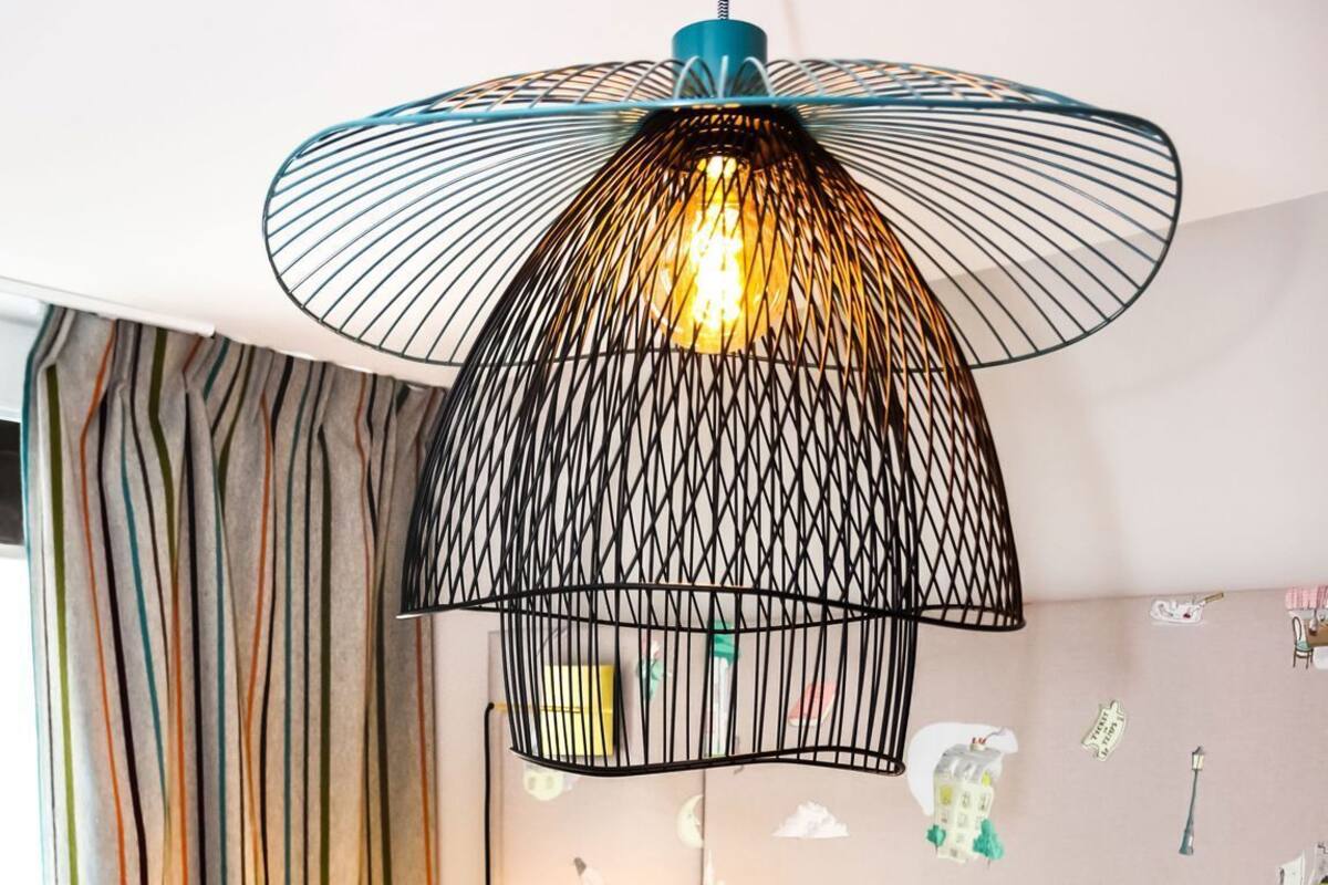 A hotel room with a bed, a chair, a desk, a lamp, and a wall with stickers.