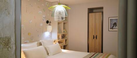 Une chambre à coucher comprenant un lit, une table de chevet, une lampe, une armoire et un luminaire suspendu.