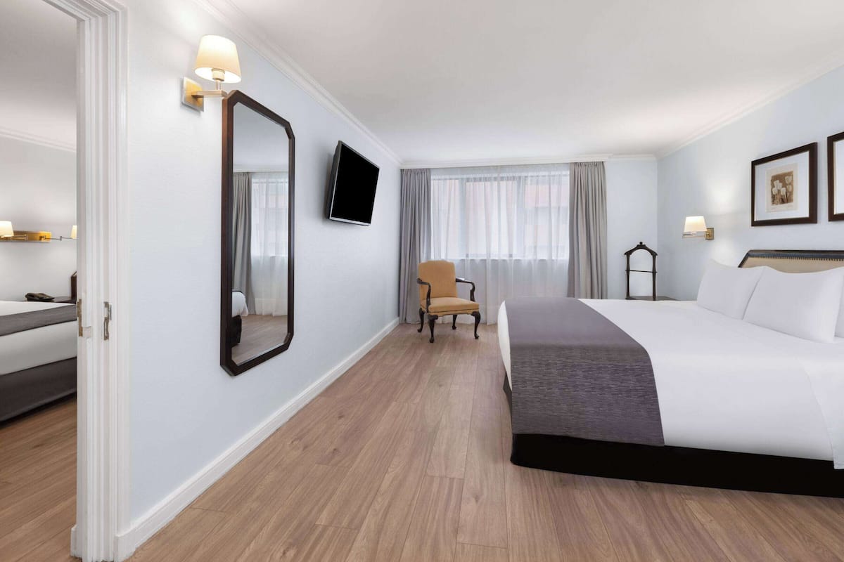 Habitación de hotel con una cama grande, una silla, un televisor y una ventana con cortinas.