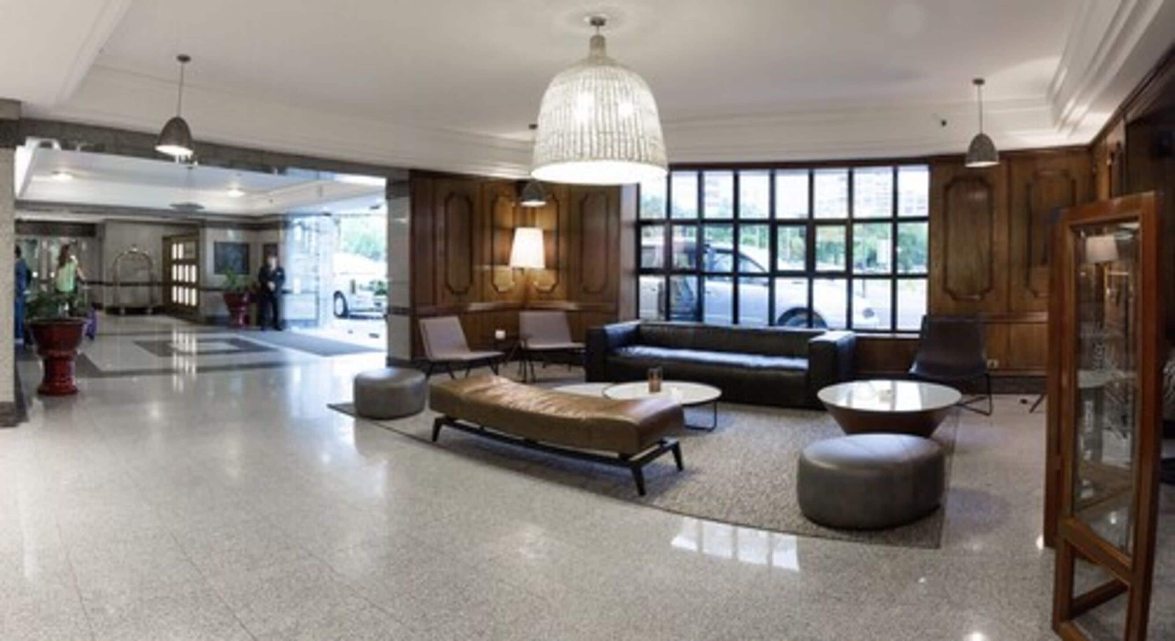 A spacious lobby with a modern sofa, a round coffee table, and a large chandelier.
